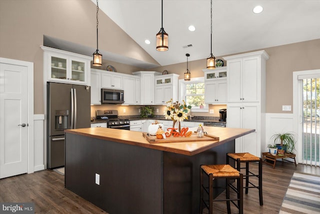 kitchen featuring butcher block countertops, a center island, appliances with stainless steel finishes, and white cabinetry