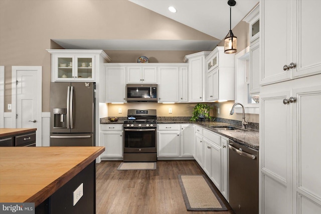 kitchen featuring hanging light fixtures, appliances with stainless steel finishes, vaulted ceiling, wooden counters, and sink