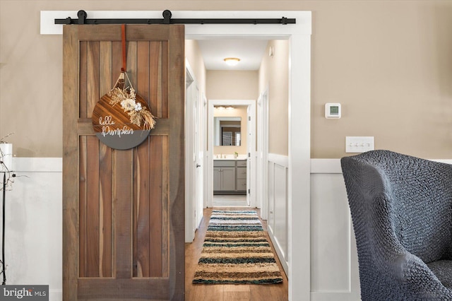 corridor with a barn door and hardwood / wood-style flooring