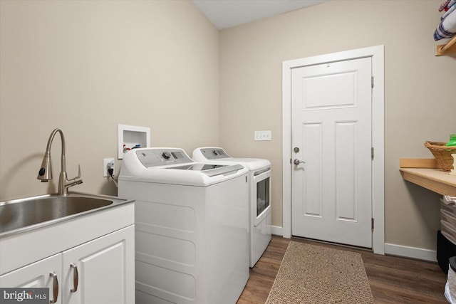 washroom featuring washing machine and dryer, sink, dark hardwood / wood-style floors, and cabinets