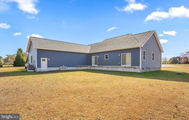 back of property with central air condition unit and a lawn