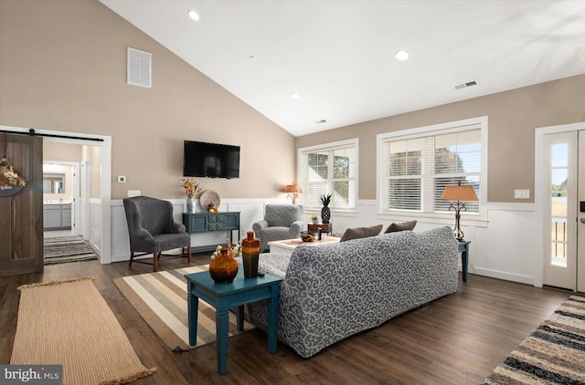 living room with a barn door, dark hardwood / wood-style floors, and high vaulted ceiling