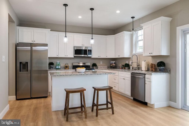 kitchen with white cabinets, sink, a kitchen island, and appliances with stainless steel finishes