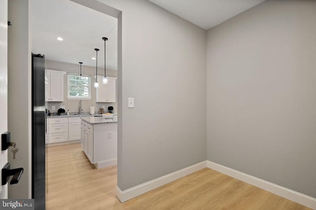 kitchen featuring pendant lighting, light hardwood / wood-style floors, white cabinetry, and sink