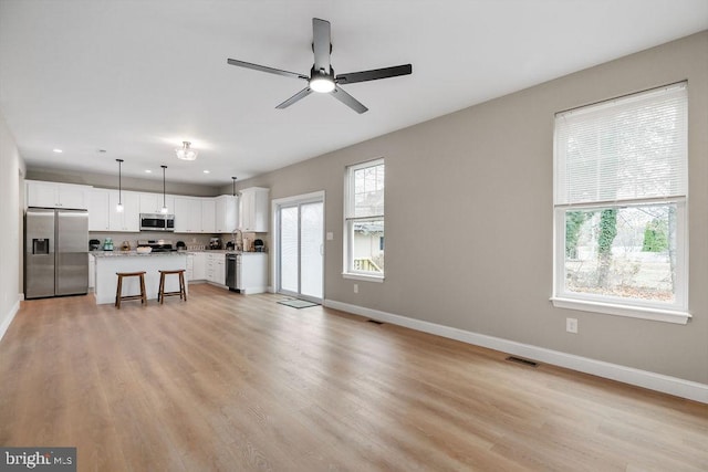 unfurnished living room with ceiling fan, sink, and light hardwood / wood-style flooring