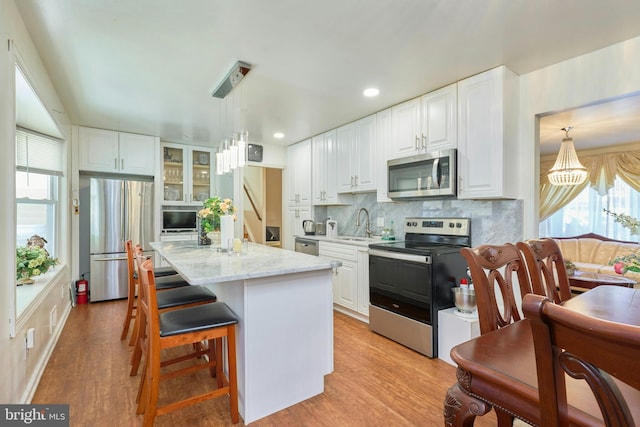 kitchen featuring white cabinets, light hardwood / wood-style floors, a center island with sink, and stainless steel appliances