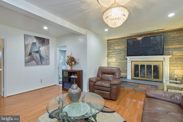 living room with a chandelier, wood-type flooring, and a fireplace