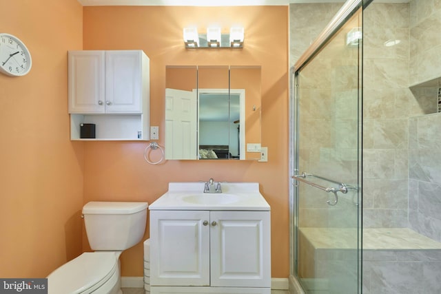 bathroom with vanity, toilet, and a shower with door