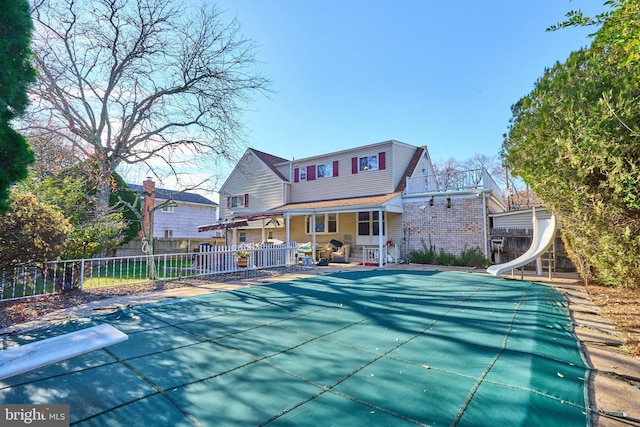 rear view of house featuring a patio and a covered pool