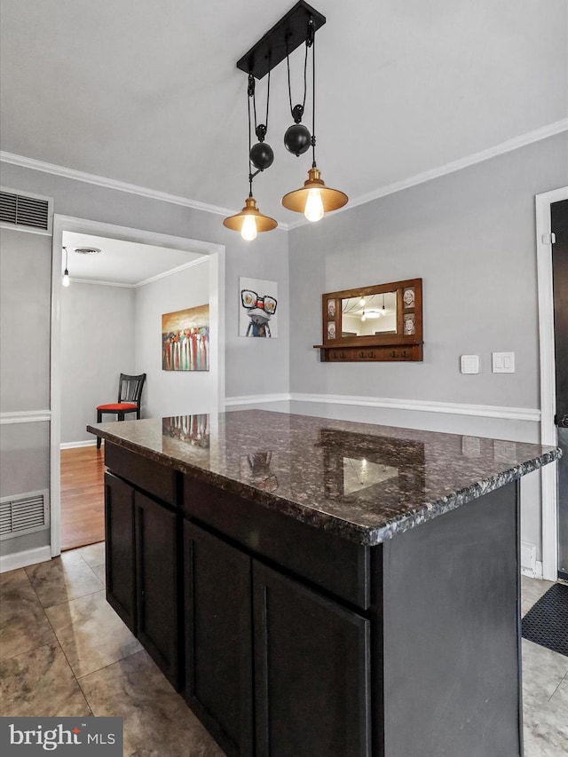 kitchen featuring pendant lighting, a center island, ornamental molding, and dark stone counters