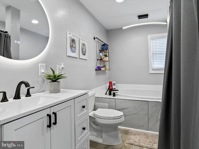 bathroom with vanity, hardwood / wood-style floors, a relaxing tiled tub, and toilet