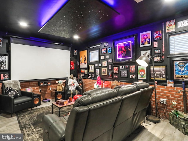 cinema featuring light wood-type flooring and brick wall