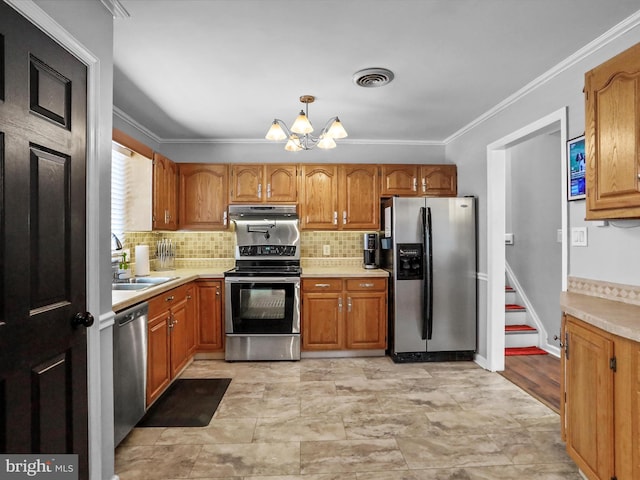 kitchen with sink, stainless steel appliances, an inviting chandelier, pendant lighting, and ornamental molding