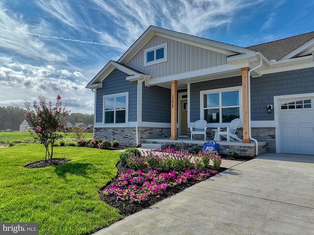 craftsman-style house featuring a front yard, covered porch, and a garage