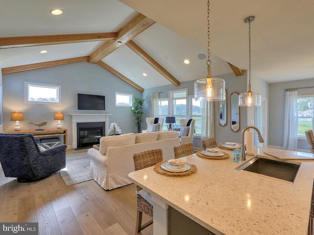 kitchen featuring a healthy amount of sunlight, sink, hanging light fixtures, and light wood-type flooring