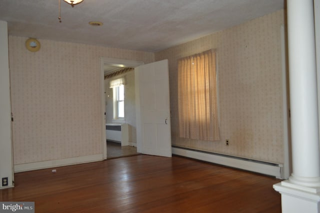 909 Ridge Rd, Westminster, MD 21157 - unfurnished living room featuring wood finished floors, wallpapered walls, a baseboard heating unit, and decorative columns