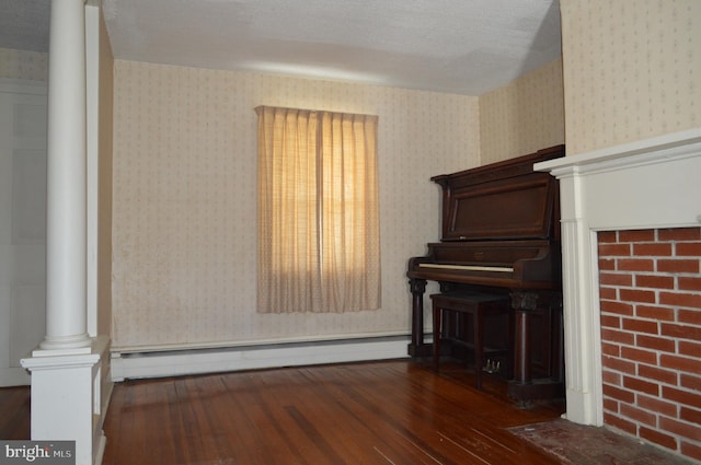 909 Ridge Rd, Westminster, MD 21157 - unfurnished living room featuring a baseboard heating unit, wallpapered walls, decorative columns, and hardwood / wood-style flooring