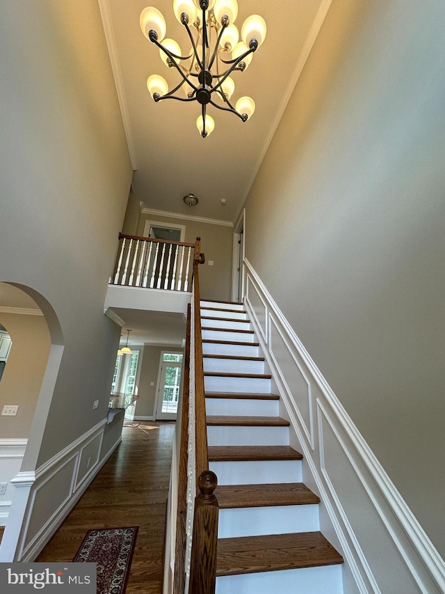 stairs with ornamental molding, a chandelier, and wood-type flooring