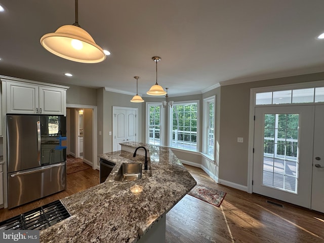 kitchen featuring plenty of natural light, white cabinets, dark stone countertops, and stainless steel refrigerator