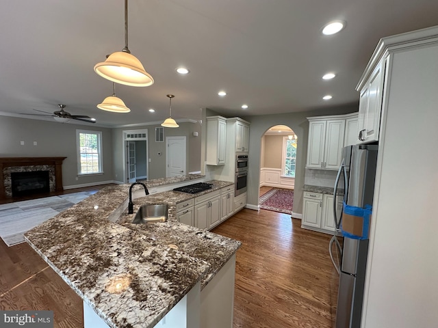 kitchen with kitchen peninsula, white cabinets, appliances with stainless steel finishes, pendant lighting, and sink