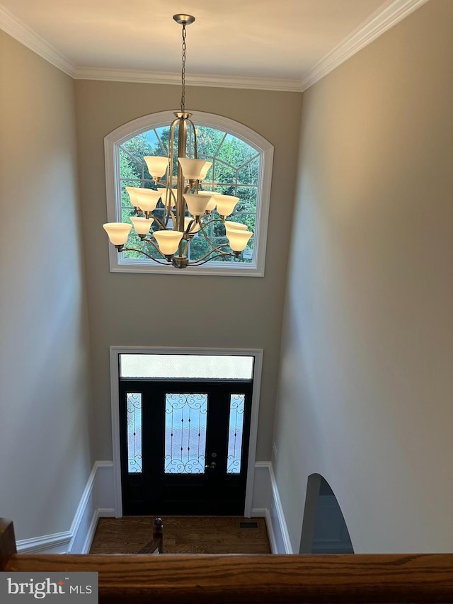 foyer entrance with a notable chandelier, a healthy amount of sunlight, and ornamental molding