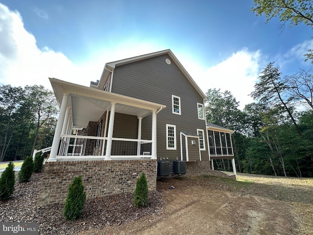 view of side of property featuring a porch, central AC unit, and a sunroom