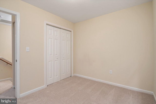 unfurnished bedroom featuring light colored carpet and a closet