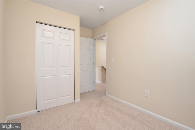 unfurnished bedroom featuring a closet and light carpet