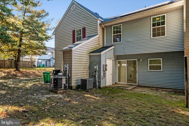 rear view of property with central AC and a lawn