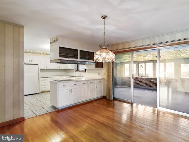 kitchen featuring light wood-type flooring, pendant lighting, white cabinets, an inviting chandelier, and white refrigerator