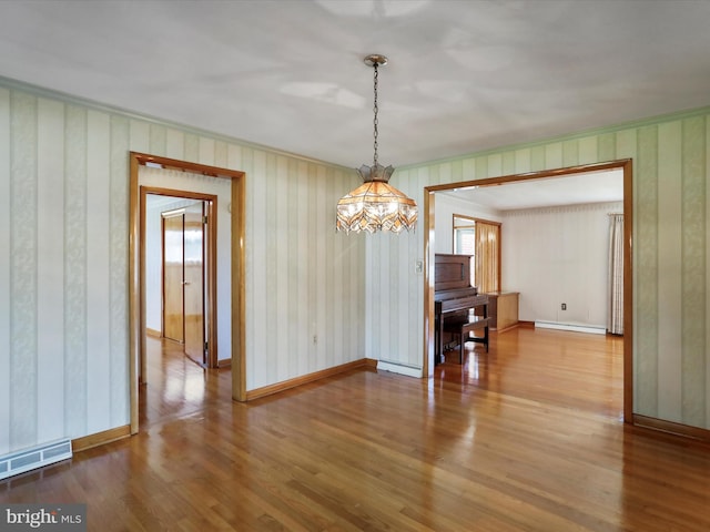 unfurnished dining area with crown molding, hardwood / wood-style flooring, and a baseboard heating unit