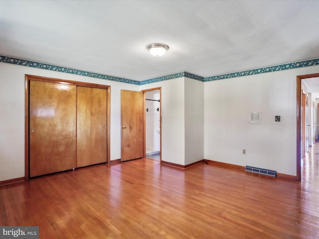 unfurnished bedroom featuring multiple closets and hardwood / wood-style floors