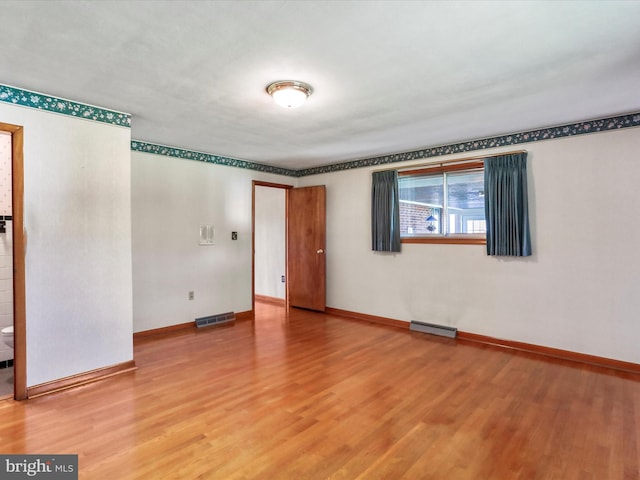 unfurnished room featuring hardwood / wood-style flooring and a baseboard radiator