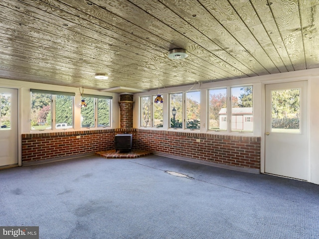 unfurnished sunroom featuring a wood stove and wooden ceiling