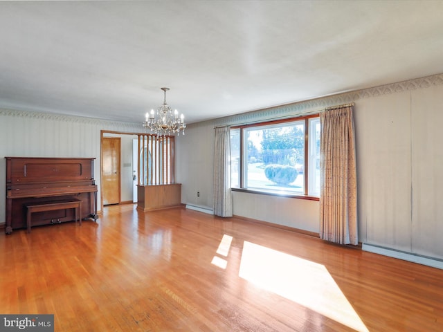 unfurnished living room with an inviting chandelier, a baseboard heating unit, and light hardwood / wood-style floors