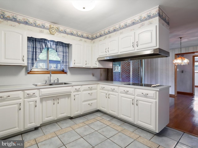 kitchen featuring kitchen peninsula, white cabinetry, light wood-type flooring, decorative light fixtures, and black stovetop