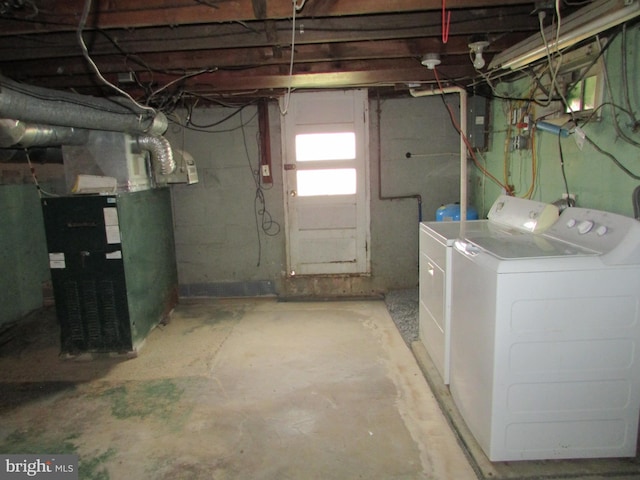 basement with electric panel, heating unit, and washing machine and clothes dryer