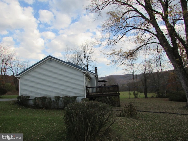 view of side of property featuring a yard and a wooden deck