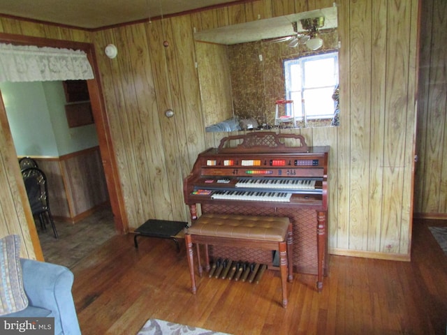 miscellaneous room featuring wood walls, ceiling fan, and wood-type flooring