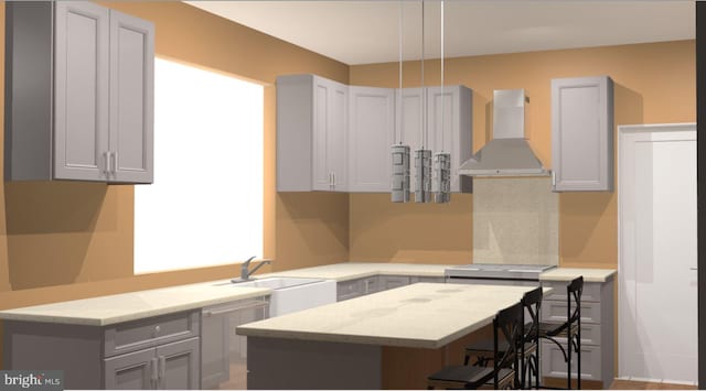 kitchen with a kitchen bar, a sink, light stone counters, a kitchen island, and wall chimney range hood