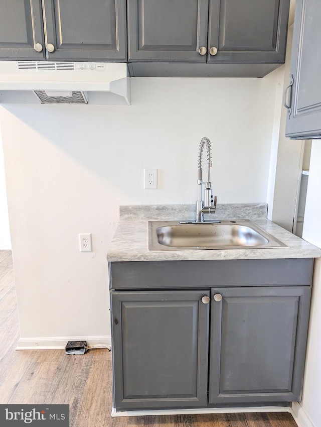 5200 Ballman, Brooklyn, MD 21225 - bar featuring a sink, wood finished floors, under cabinet range hood, and baseboards