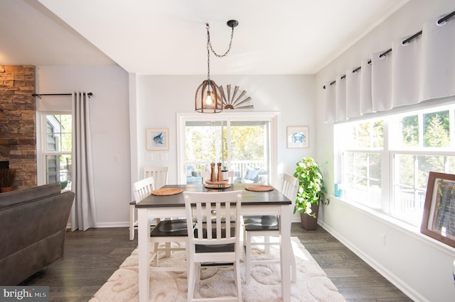 dining space with dark wood-type flooring, plenty of natural light, and an inviting chandelier