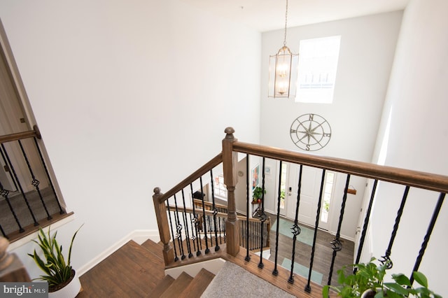 stairway featuring wood-type flooring and a notable chandelier