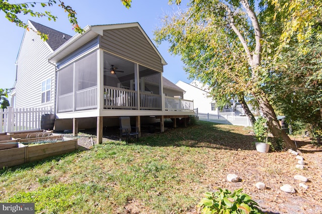 back of property with ceiling fan, a lawn, and a sunroom