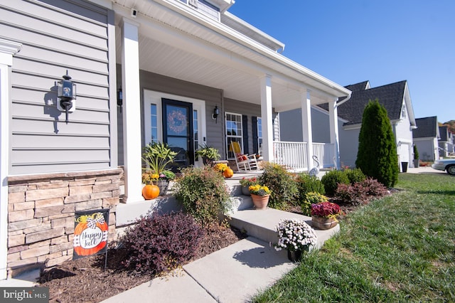 doorway to property with covered porch and a yard