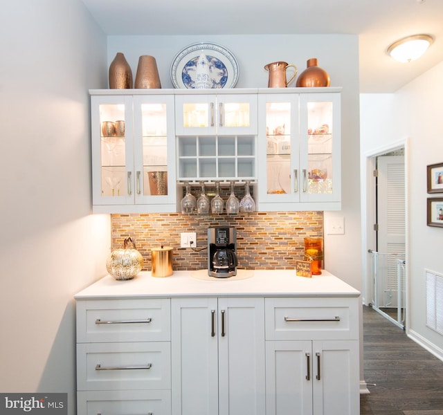 bar with white cabinetry, backsplash, and dark hardwood / wood-style flooring