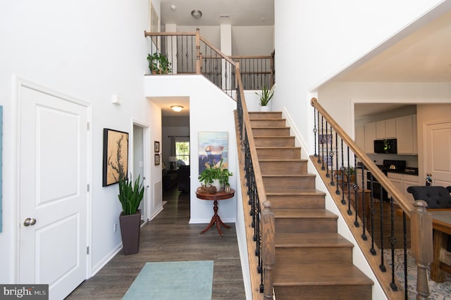 stairway featuring hardwood / wood-style flooring and a towering ceiling