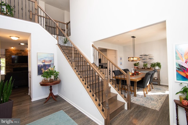 stairway featuring a high ceiling, a chandelier, and wood-type flooring