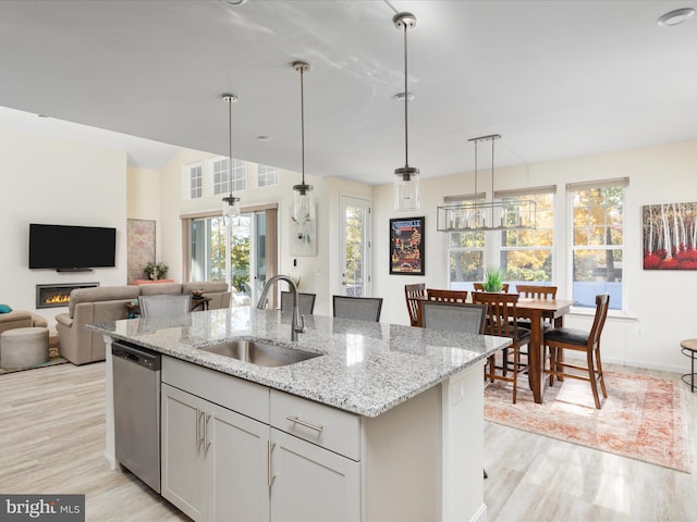 kitchen featuring stainless steel dishwasher, sink, light hardwood / wood-style flooring, and plenty of natural light