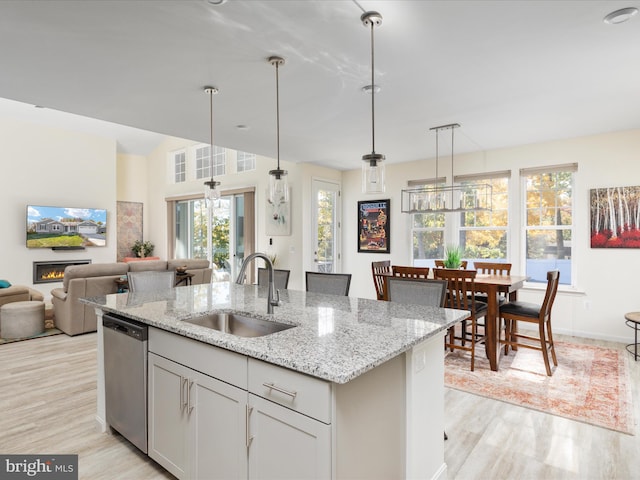 kitchen featuring a healthy amount of sunlight, sink, light wood-type flooring, and dishwasher